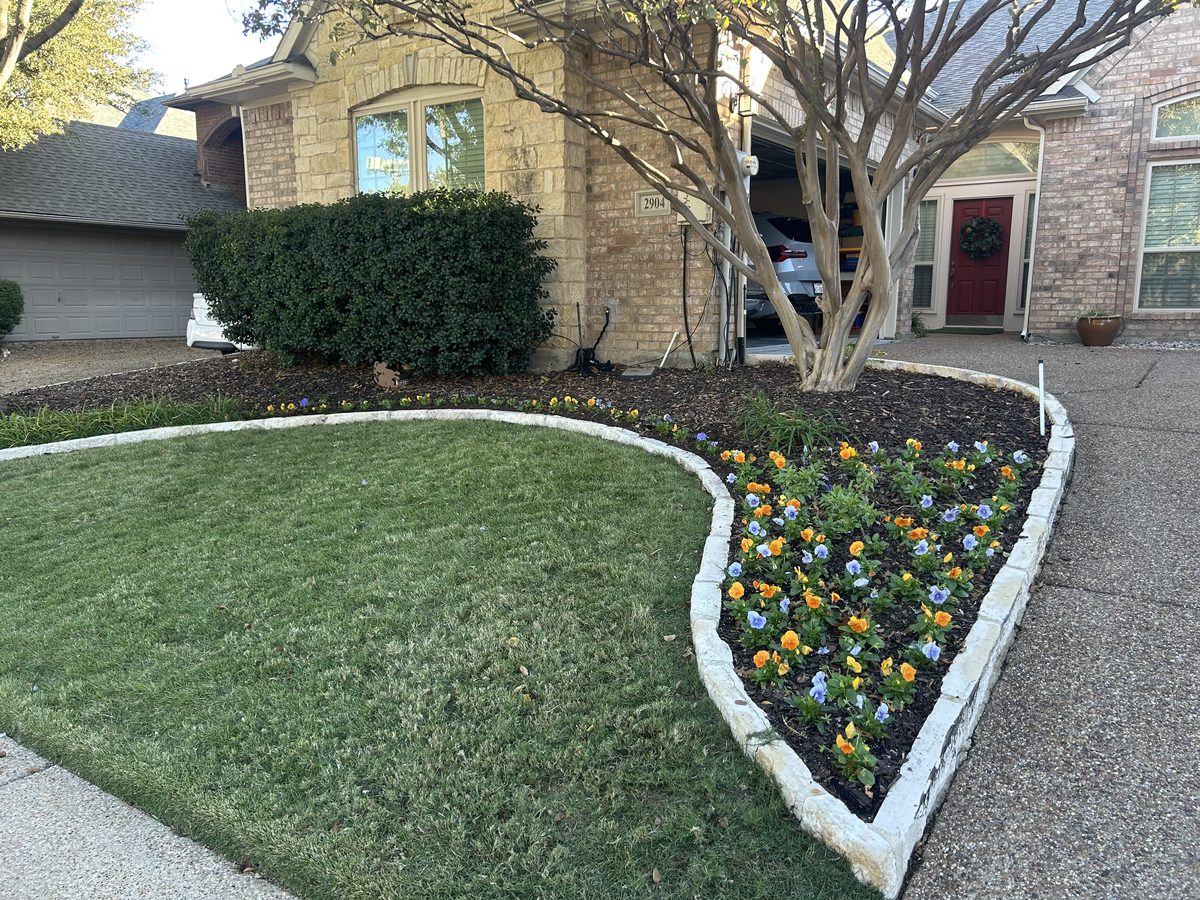 Stone edging with seasonal flowers by DFW Lawn Care Pros